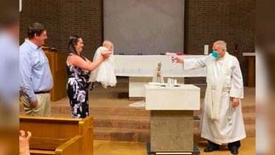Photo of Priest performs socially-distanced baptism on baby using water pistol